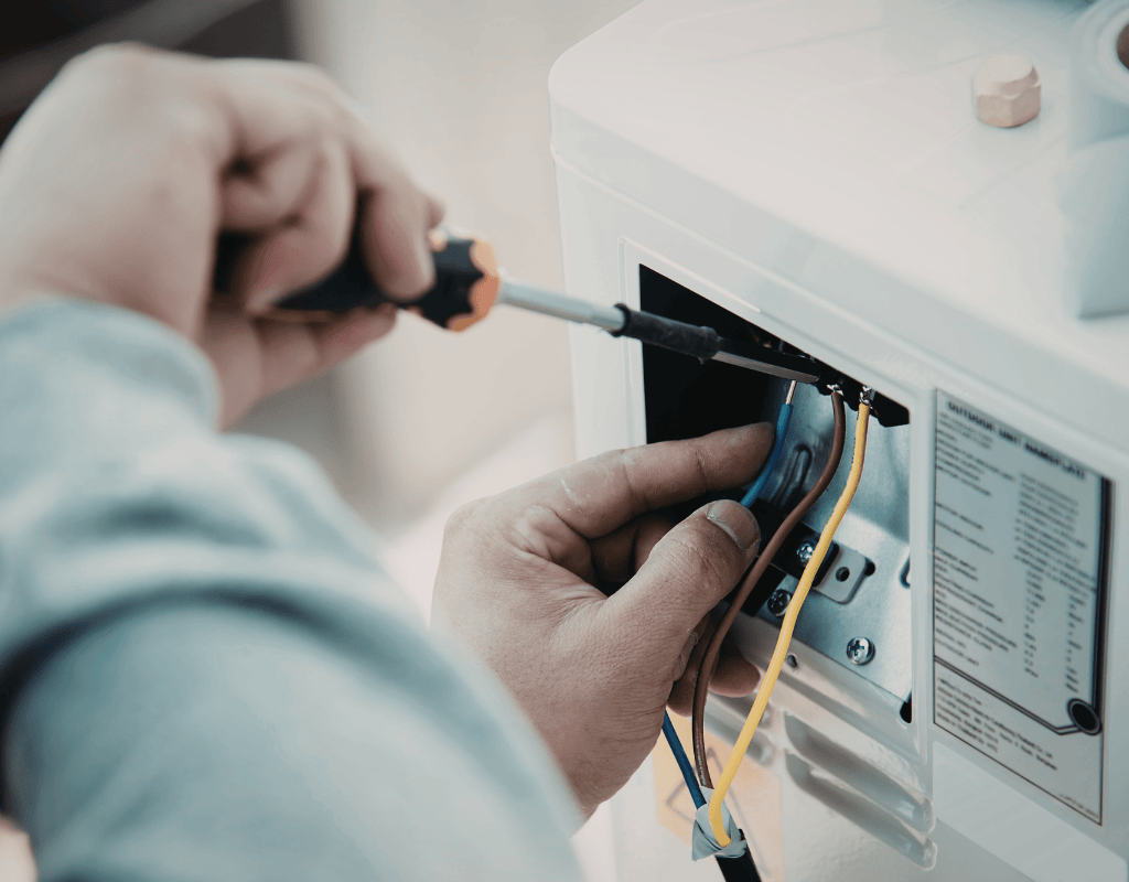 Electrician repairing internal wiring of electrical unit using screwdriver in North Shore MA